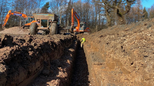 Cross section of the trench showing stepped sides for safety. Pipe laid and backfilled with 40 mm stone