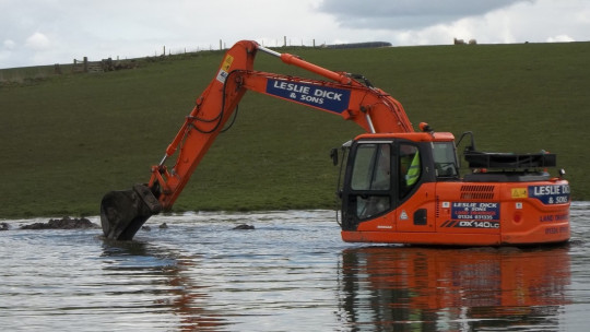 Swimming digger! Draining the flodded part of the field into the new leader